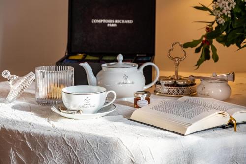 a table with a book and a cup and a tea pot at Le Pavillon des Lys - Hôtel Particulier in Amboise