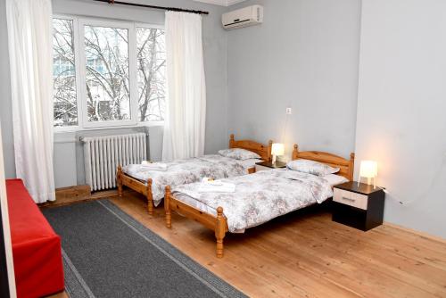 two beds in a room with a red couch and a window at Santa Sofia in Sofia