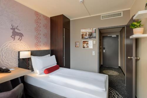 a bedroom with a white bed with a red pillow at Mercure München City Center in Munich