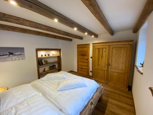 a bedroom with a white bed and wooden floors at Chalet Apartments Maštal in Železná Ruda