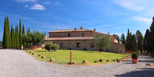 una vecchia casa in pietra con un prato davanti di Agriturismo Bonello a Pienza