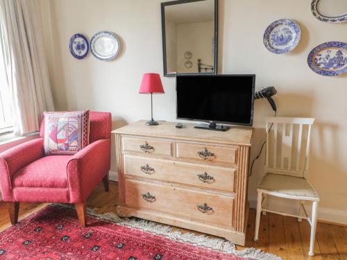 a living room with a tv and a chair and a dresser at Lower Cross in Keighley