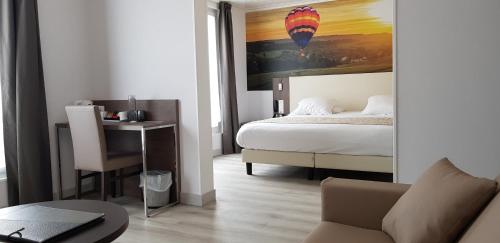 a bedroom with a bed and a desk with a laptop at Best Western Hotel Ile de France in Château-Thierry