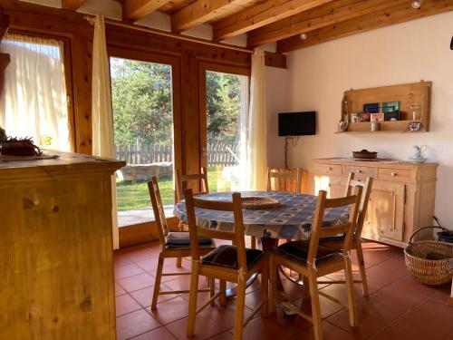 ein Esszimmer mit einem Tisch, Stühlen und einem Fenster in der Unterkunft Eco Chalet Nonno Silvano in Bedollo