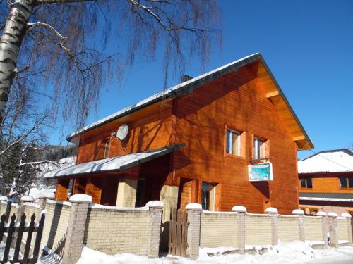 a wooden building with a fence in the snow at Під каштаном in Vorokhta