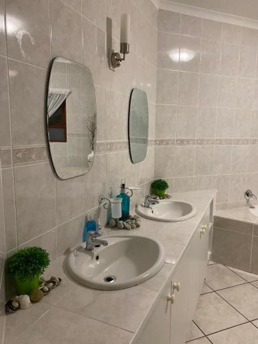 a bathroom with two sinks and a mirror and a tub at Sea Jewel in Pearly Beach