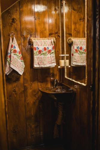 a bathroom with a sink and a mirror and towels at Kolyba Opryshkiv in Nizhneye Selishche