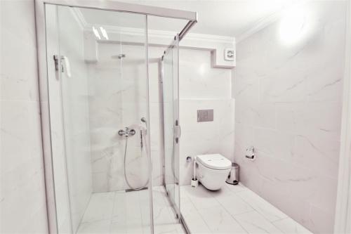 a white bathroom with a shower and a toilet at Club Çapa Hotel in Kas