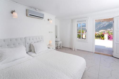 a white bedroom with a white bed and a window at Club Çapa Hotel in Kas