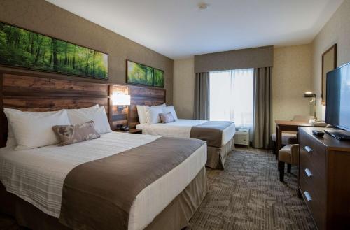 a hotel room with two beds and a flat screen tv at BEST WESTERN PLUS Valemount Inn & Suites in Valemount