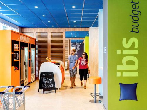 two people walking down a hallway in a store at ibis budget Sao Caetano in São Caetano do Sul