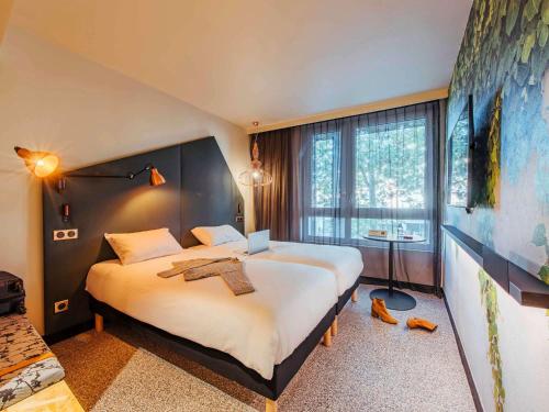 ルーアンにあるIbis Styles Rouen Centre Rive Gaucheのベッド2台と大きな窓が備わるホテルルームです。
