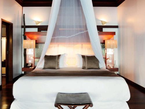 a bedroom with a large white bed with a canopy at Sofitel Kia Ora Moorea Beach Resort in Maharepa