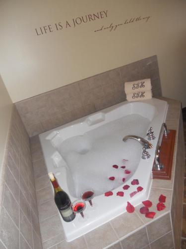 a bath tub with a bottle of wine and hearts at Sandhills Guest House Motel in Atkinson