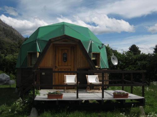 a tree house with two chairs in front of it at Domos Puelo in Lago Puelo