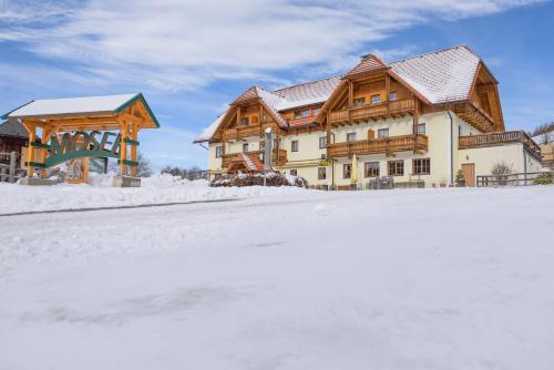 a large wooden house in the snow in front at Alpengasthof Moser in Karchau