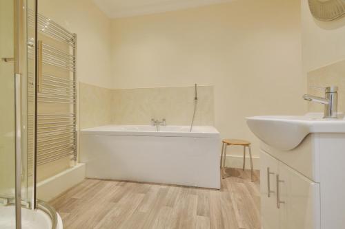 a white bathroom with a tub and a sink at Scarborough Penthouse, private balcony, superb views, lift, reserved free parking in Scarborough