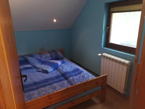 卡路耶斯科巴雷的住宿－Apartmani Popovic，一间卧室配有一张蓝色墙壁的床和一扇窗户