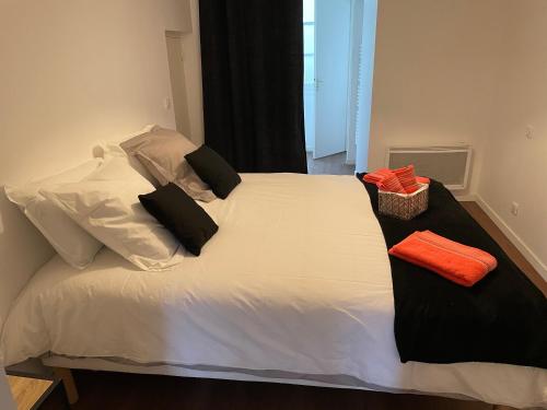 a white bed with black pillows on top of it at T1 bis 35 m2 lit queen size tout équipé in Pau