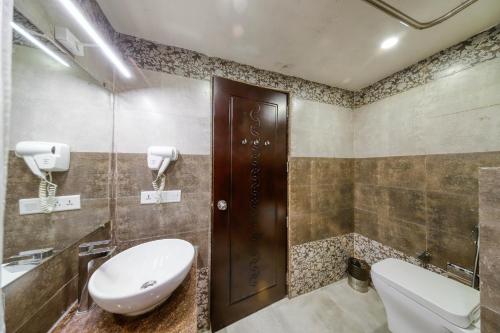 a bathroom with a toilet and a sink at Regenta Inn Vadodara, 500m from Railway Station in Vadodara
