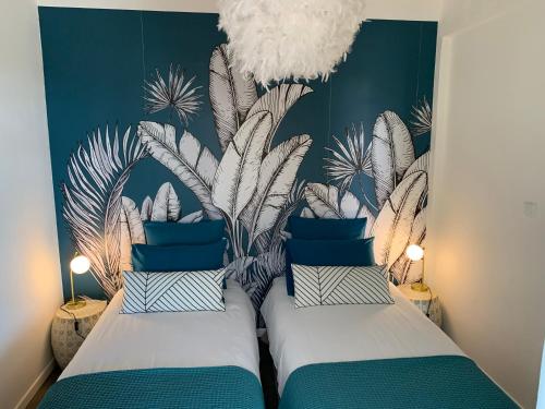 2 letti in una camera con un murale di piante di Villa Miss Satô a Ravine des Cabris