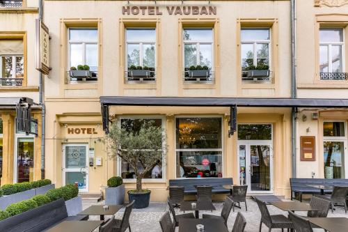 a hotel with tables and chairs in front of a building at Hotel Vauban in Luxembourg
