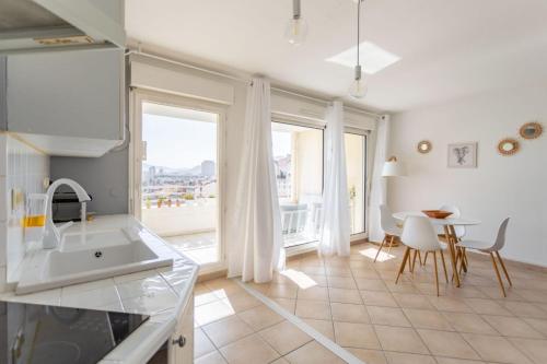 une cuisine avec un évier et une table avec des chaises dans l'établissement Appartement Standing Marseille 2 chambres 6 pers Clim Parking JO, à Marseille