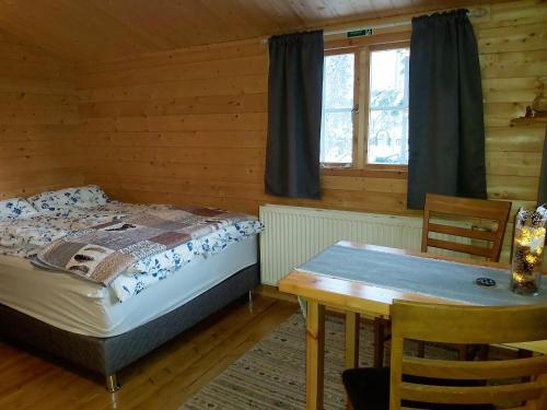 a bedroom with a bed and a table and a window at Bakkakot 2 - Cozy Cabins in the Woods in Akureyri
