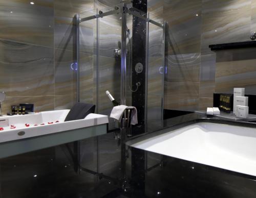 a bathroom with a shower and a sink and a tub at Swiss Flora Royal Hotel Riyadh in Riyadh