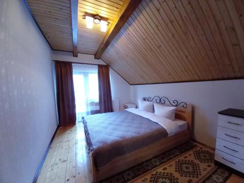 a bedroom with a bed with a wooden ceiling at Котедж "Хата край села" in Tatariv