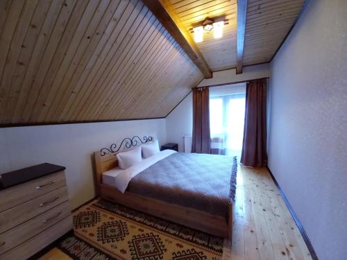 a bedroom with a bed and a large window at Котедж "Хата край села" in Tatariv