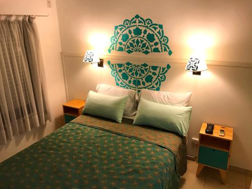 1 dormitorio con 1 cama con colcha verde y 2 lámparas en Mandalas 1, amplio apartamento en Belén de Escobar