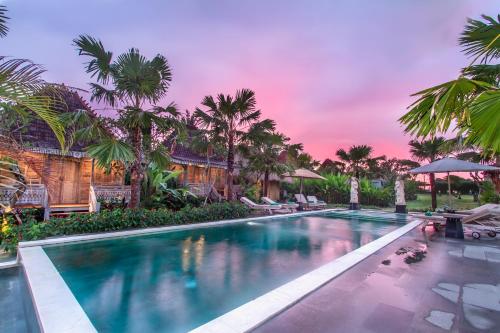 a swimming pool with palm trees in a resort at Aswanaya Villas Ubud in Ubud