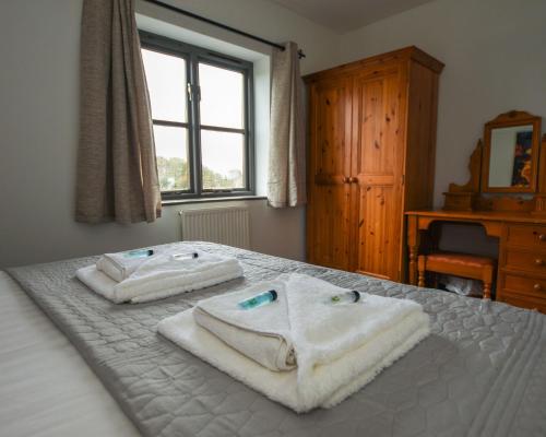 a bedroom with two towels on a bed with a window at Conwy Valley Hotel Cottages in Conwy