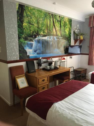 a bedroom with a large painting of a waterfall on the wall at The Nyton Guesthouse in Ely