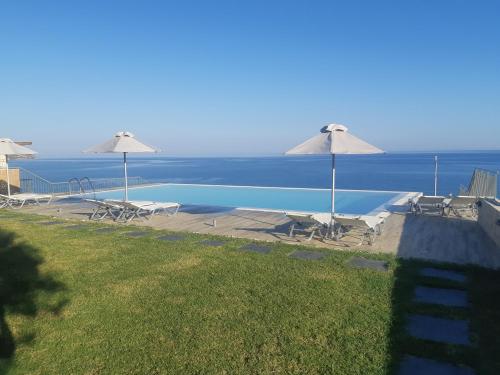 a swimming pool with umbrellas and the ocean at Portela Apartments Kastri in Keratokampos