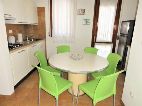 una cucina con tavolo bianco e sedie verdi di Villa Agavi 3 a Bibione