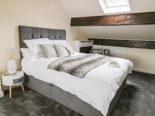 1 dormitorio con 1 cama grande con sábanas y almohadas blancas en Little Barn en Keighley
