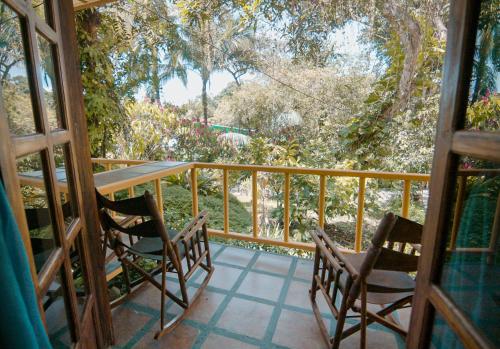 a porch with two chairs and a table on a balcony at Hotel Tres Banderas in Manuel Antonio