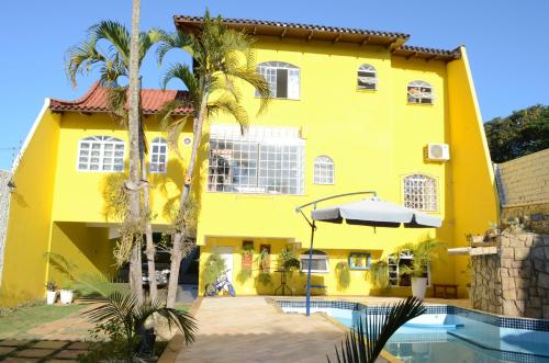 a yellow house with a swimming pool and palm trees at La Maison Brasiliana B&B in Foz do Iguaçu