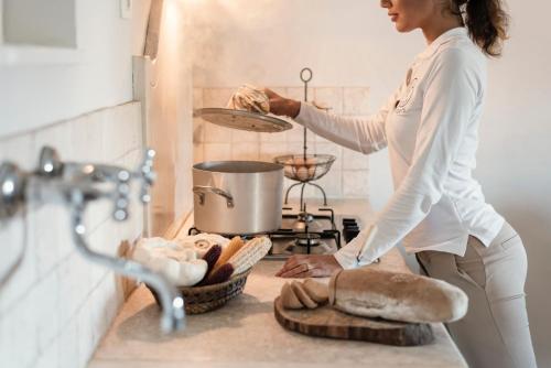 kobieta stojąca w kuchni przygotowująca jedzenie w piekarniku w obiekcie Il Cantinone w mieście San Vincenzo