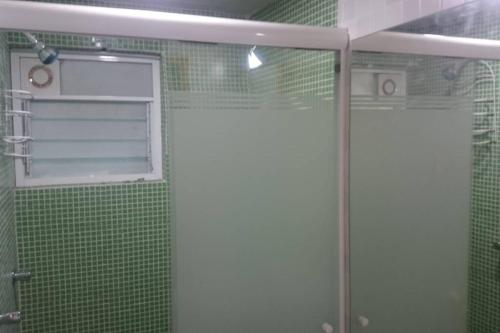 y baño con ducha de azulejos verdes y puerta de cristal. en San Marino, en San Francisco Tlalnepantla