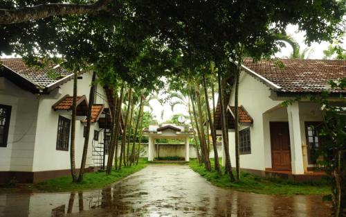 a row of trees in front of a house at Carpe DiemStay in Kushālnagar