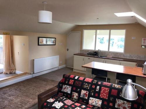 a living room with a couch and a kitchen at The Garden Loft in Freethorpe