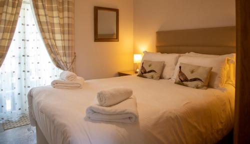 um quarto com uma cama branca e toalhas em The Cottage em Benllech