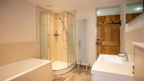 uma casa de banho com um chuveiro, um lavatório e uma banheira em The Cottage em Benllech