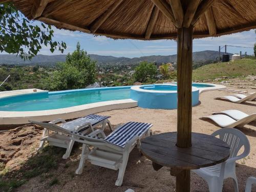 un patio con mesa, sillas y piscina en Cabañas Los Álamos en Villa Carlos Paz