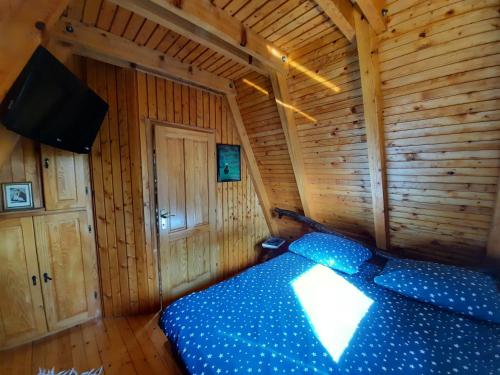 Planinska kuca Dasovic في فوزين: غرفة نوم بسرير ازرق في غرفة خشبية