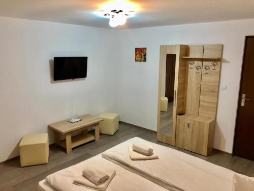 a white room with a bed and a tv and a table at Casa Truța in Topliţa