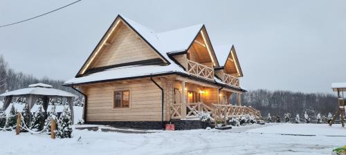 a log cabin with snow on the roof at Bieszczadzkie Chaty in Polańczyk